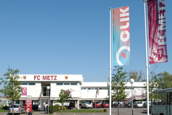 Photo illustrant les drapeaux CLIK management devant l'académie de football du FC Metz